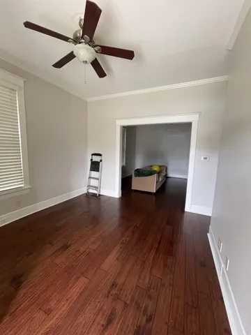 a view of empty room with wooden floor and ceiling fan