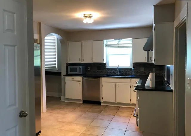 a kitchen with granite countertop a sink a stove and cabinets