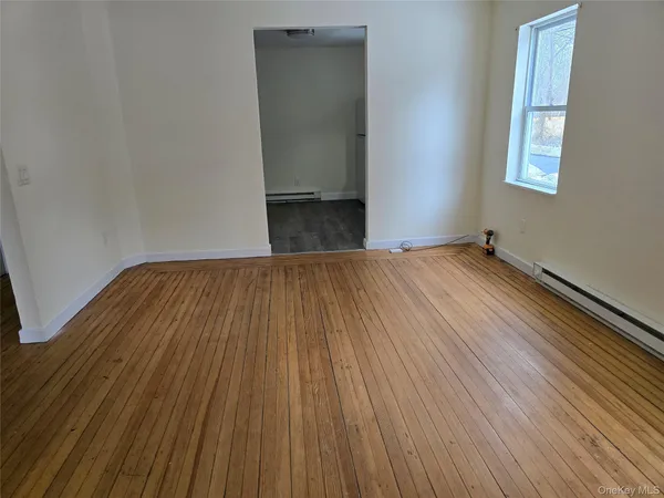 a view of an empty room with wooden floor and a window