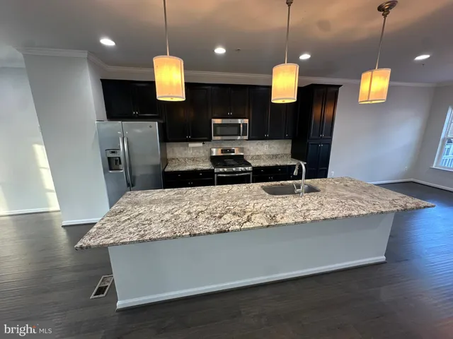 a kitchen with kitchen island stainless steel appliances sink and wooden floor
