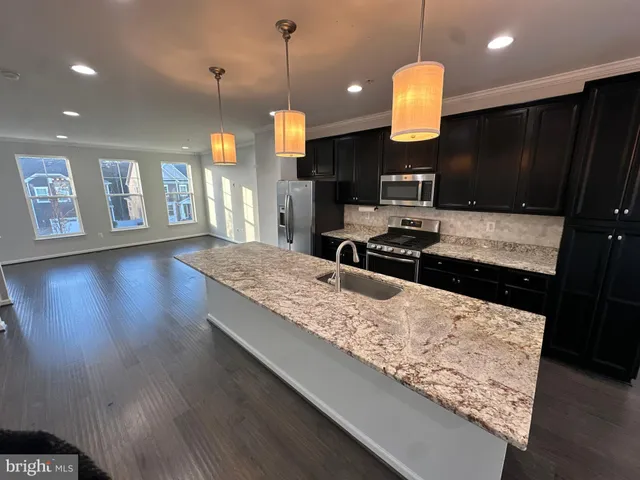 a large kitchen with stainless steel appliances kitchen island granite countertop a stove a refrigerator and a wooden floors