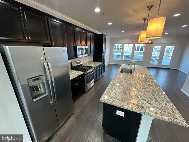 a kitchen with stainless steel appliances granite countertop a refrigerator a stove and a wooden floors