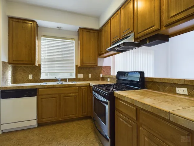 a kitchen with stainless steel appliances granite countertop a sink a stove and a refrigerator