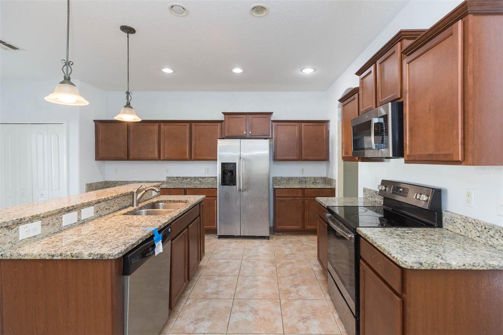 1803 Palm Warbler Lane Ruskin, FL 33570 - Photo 12 of 51 a kitchen with stainless steel appliances granite countertop a sink stove and refrigerator