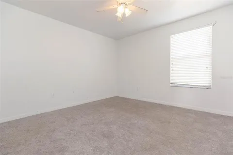 an empty room with a chandelier fan and closet area