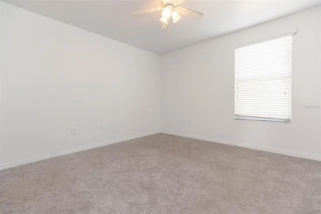 an empty room with a chandelier fan and closet area