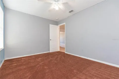 an empty room with a window and a ceiling fan