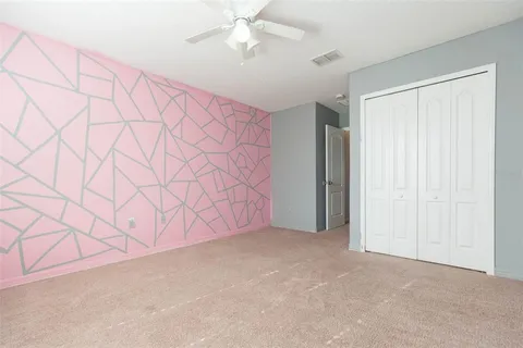 an empty room with a window and a chandelier fan