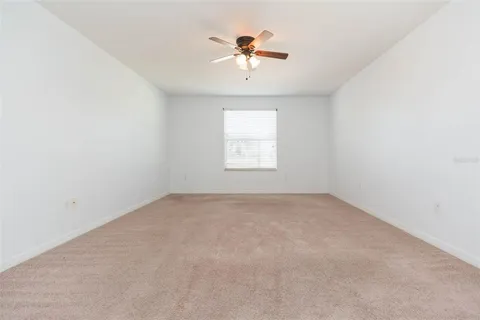 an empty room with a chandelier fan and windows