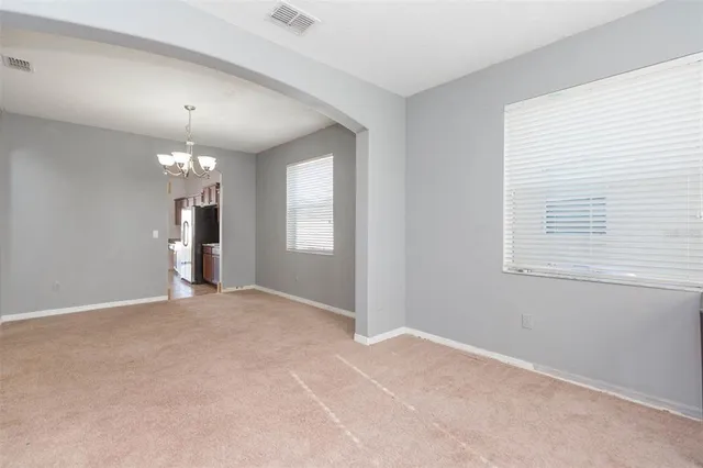 an empty room with chandelier fan and windows