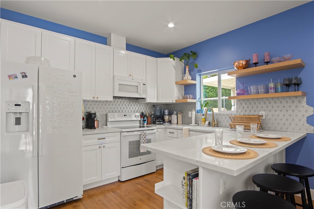 6835 Aldea Avenue Van Nuys, CA 91406 - Photo 37 of 50 a kitchen with stainless steel appliances granite countertop a sink a stove a refrigerator and white cabinets with wooden floor
