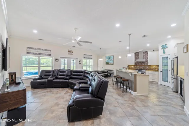 a kitchen with stainless steel appliances kitchen island a large island a stove a refrigerator and chairs