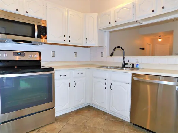 a kitchen with stainless steel appliances a stove microwave and sink