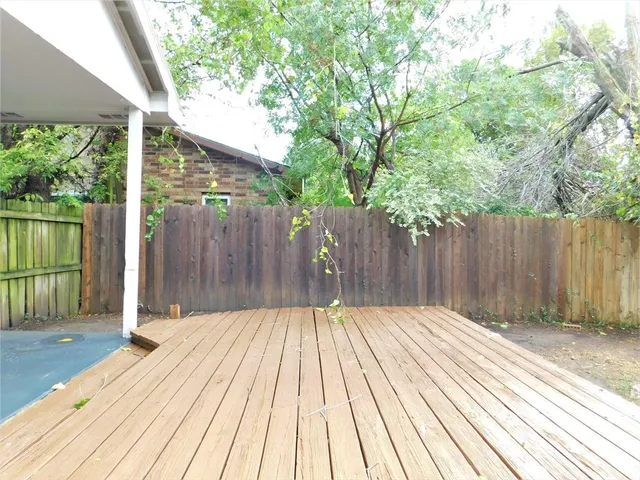 a view of a backyard with large trees and wooden fence