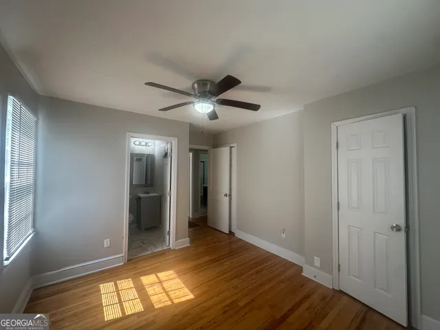 a view of empty room with wooden floor and fan