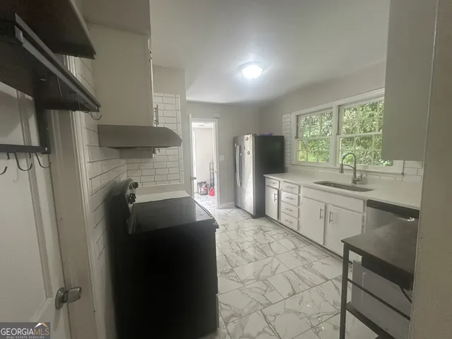 a kitchen with a sink a refrigerator and cabinets