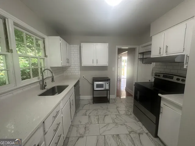 a kitchen with granite countertop a stove sink and refrigerator