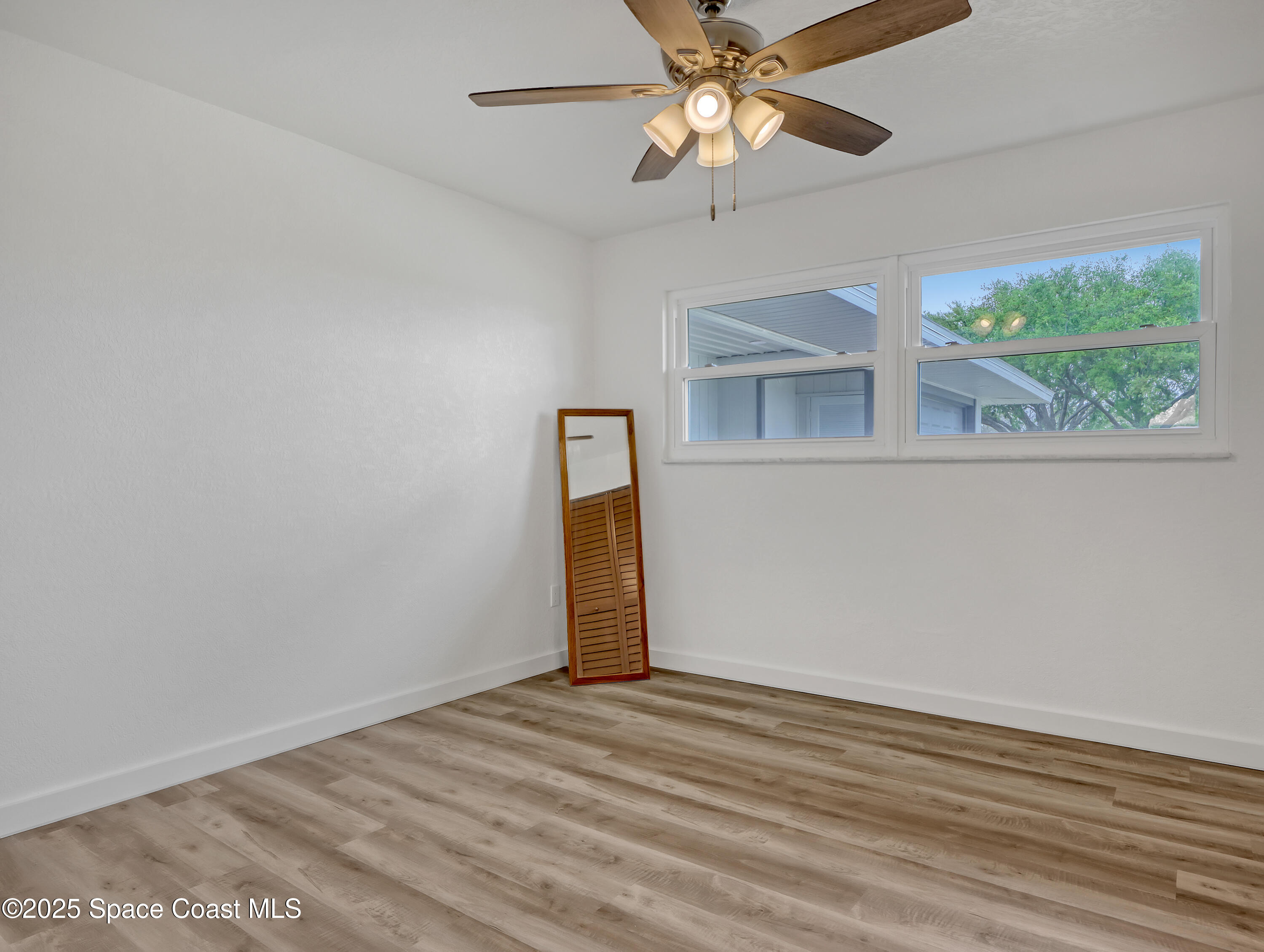 872 Sadnet Circle Northeast Palm Bay, FL 32905 - Photo 12 of 21 en empty room with wooden floor fan and window