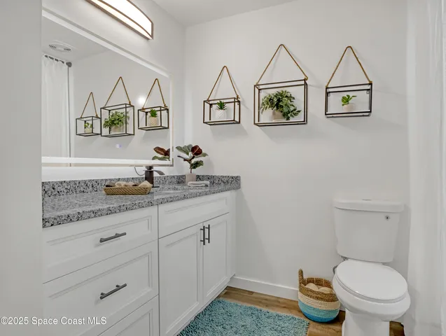 a bathroom with a granite countertop toilet and a sink
