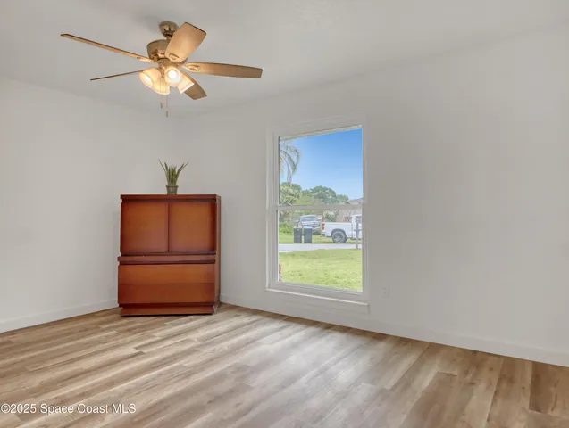an empty room with a window and a ceiling fan