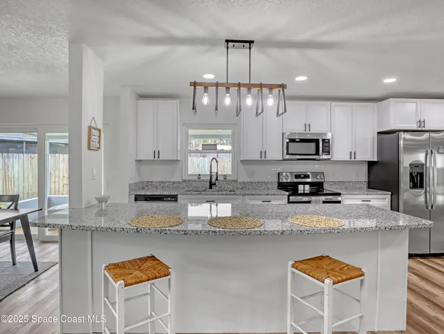 a kitchen with stainless steel appliances granite countertop a sink refrigerator stove and microwave