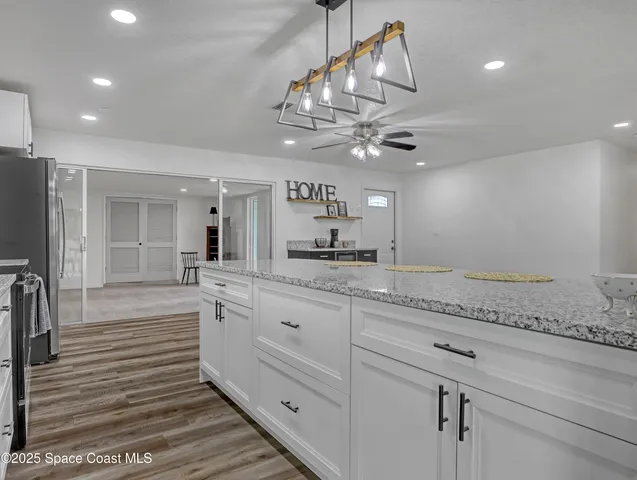 a large kitchen with granite countertop a large counter space and stainless steel appliances