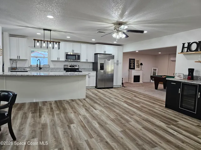 a kitchen with stainless steel appliances granite countertop a refrigerator a sink dishwasher a stove and white countertops with wooden floor