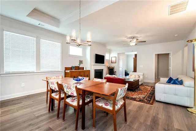 a kitchen with stainless steel appliances granite countertop a refrigerator a sink dishwasher a stove a dining table and chairs with wooden floor