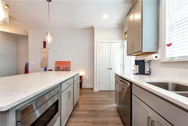 a kitchen with stainless steel appliances a sink a stove a refrigerator cabinets and wooden floor