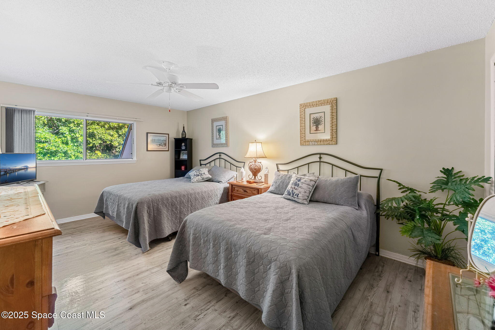 6205 Treetop Drive Melbourne Beach, FL 32951 - Photo 14 of 36 a bedroom with two beds and a potted plant on dresser