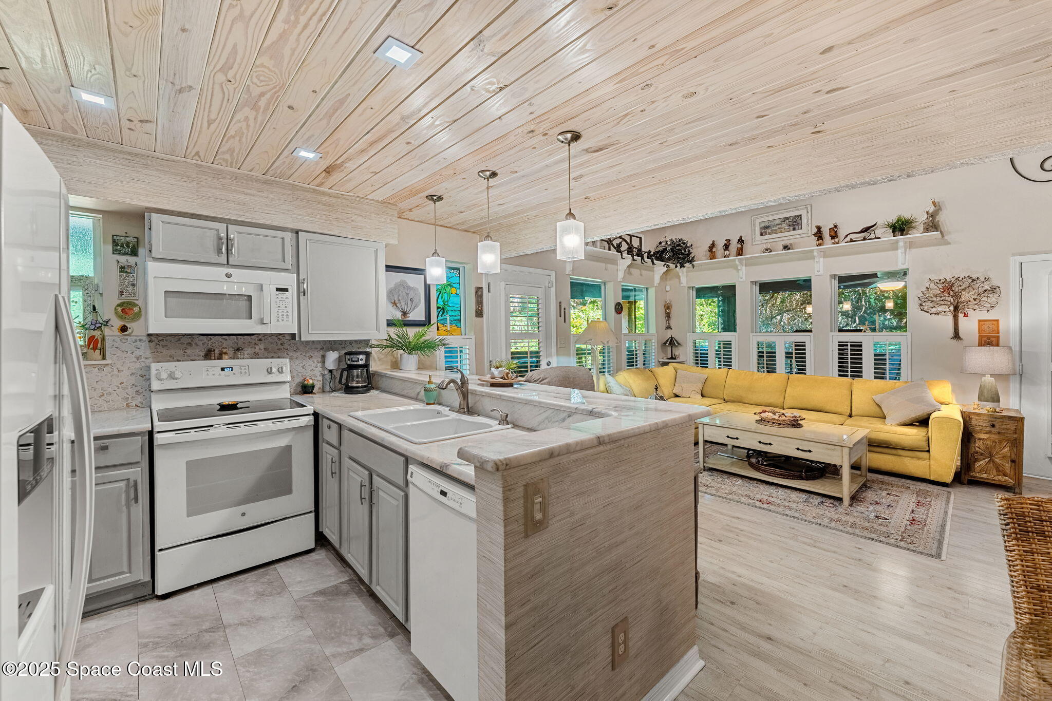 6205 Treetop Drive Melbourne Beach, FL 32951 - Photo 6 of 36 a kitchen with stainless steel appliances granite countertop a lot of counter space and wooden floors
