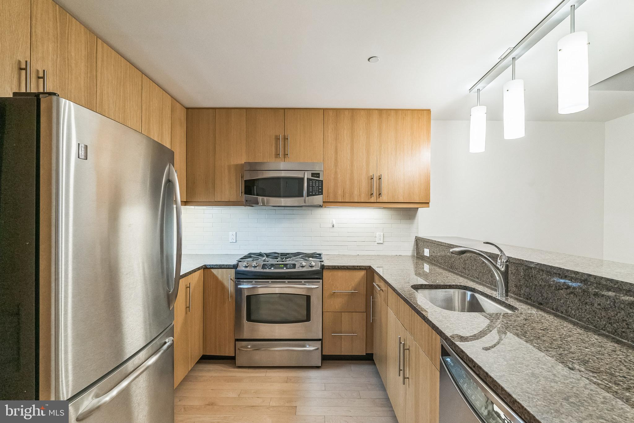 a kitchen with stainless steel appliances granite countertop a refrigerator sink and stove