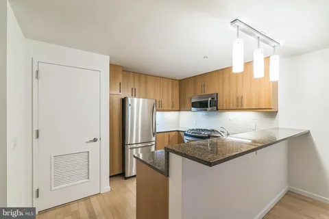 a kitchen with stainless steel appliances granite countertop a refrigerator a stove a sink and a microwave