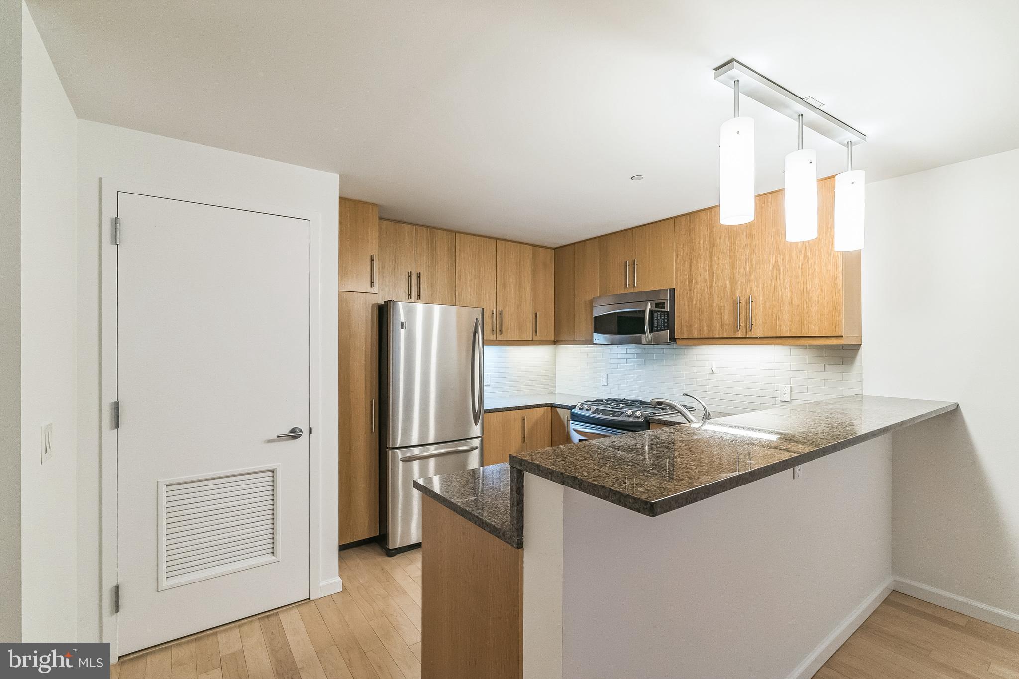 1425 Locust Street, Unit 3B Philadelphia, PA 19102 - Photo 3 of 13 a kitchen with stainless steel appliances granite countertop a refrigerator a stove a sink and a microwave