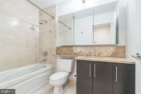 a bathroom with a granite countertop sink a toilet and shower