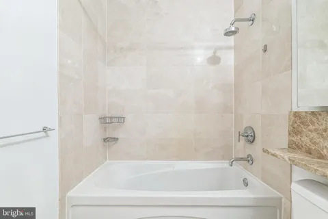 a white bath tub sitting next to a white sink and vanity