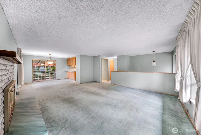 a view of an empty room with a fireplace and a window