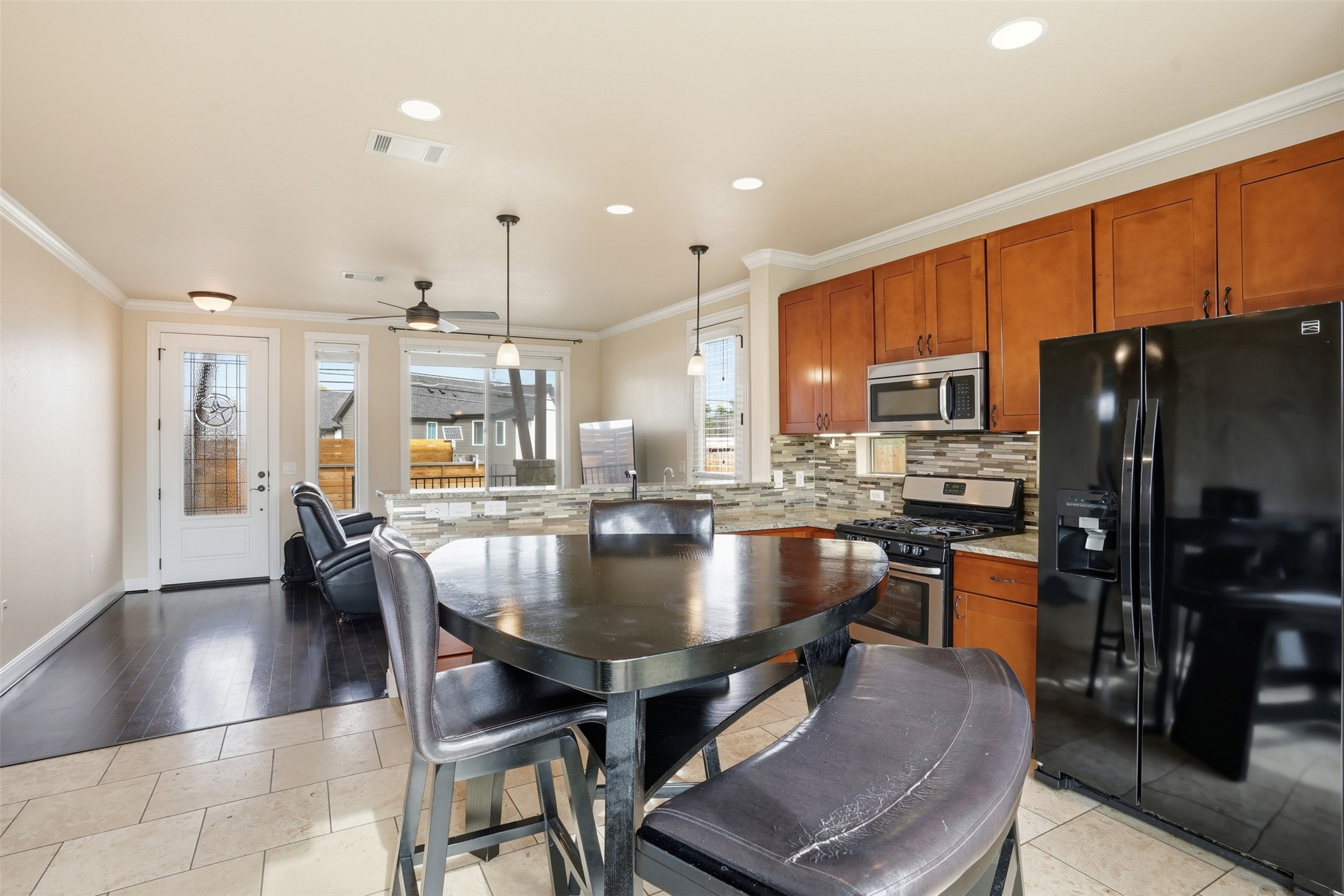 1185 Springdale Road Austin, TX 78721 - Photo 8 of 32 a kitchen with stainless steel appliances granite countertop a stove a refrigerator a kitchen island a dining table and chairs with wooden floor