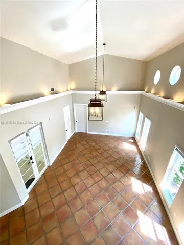 a view of an empty room with windows and chandelier