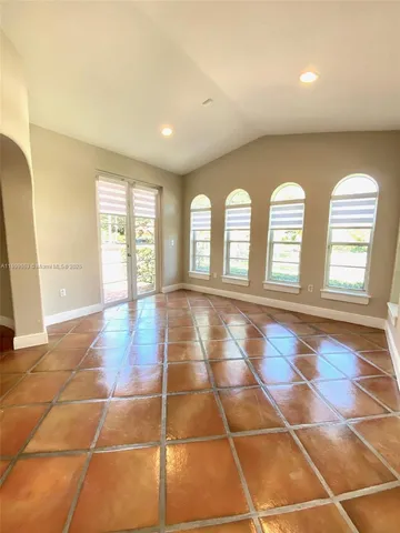 a view of an empty room with windows and chandelier fan