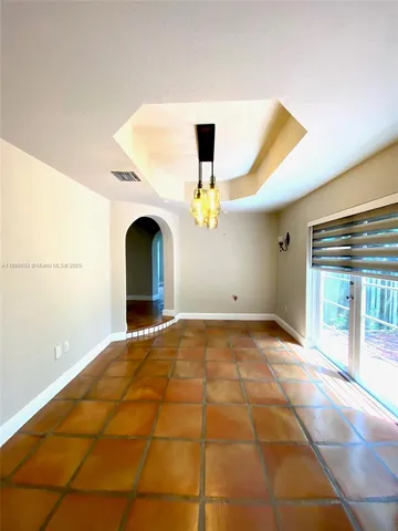 a view of an empty room with chandelier fan and a window