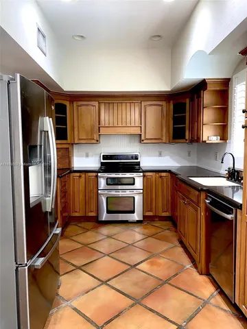 a kitchen with granite countertop a refrigerator and a stove top oven