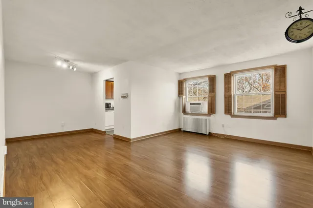 a view of an empty room with window and wooden floor