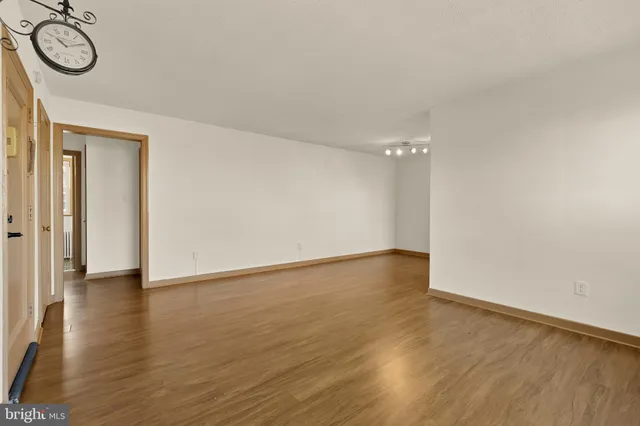 a view of empty room with wooden floor and white walls