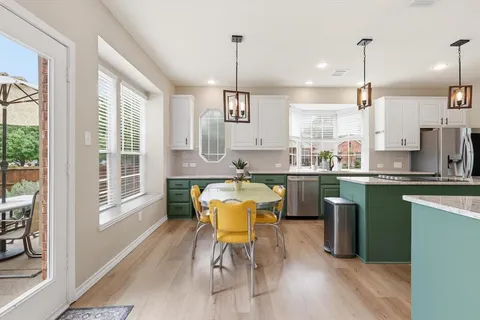 a kitchen with a table chairs wooden floors and a view of living room