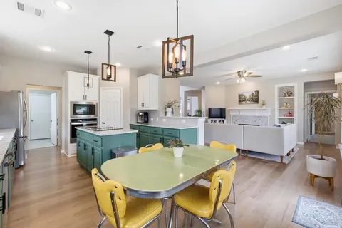 a kitchen with stainless steel appliances kitchen island granite countertop a table chairs and a refrigerator