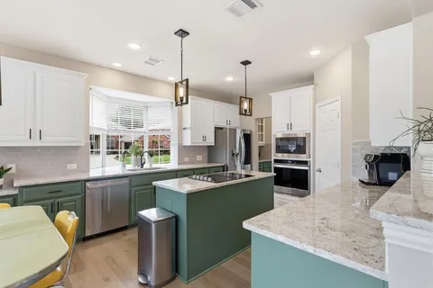 a kitchen with stainless steel appliances kitchen island granite countertop a sink a stove and a refrigerator