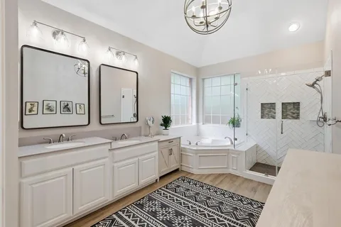a en suite bathroom with double vanity a mirror and a bathtub