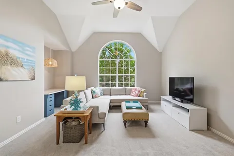 a living room with furniture a flat screen tv and a large window