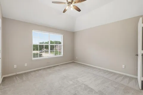 an empty room with a ceiling fan and window